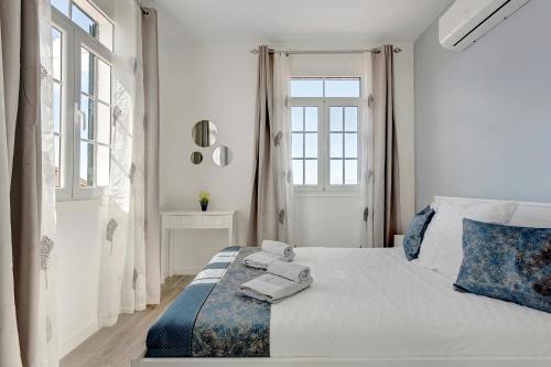 a white bedroom with a bed with towels on it at Casa Pereira in Ponta do Pargo