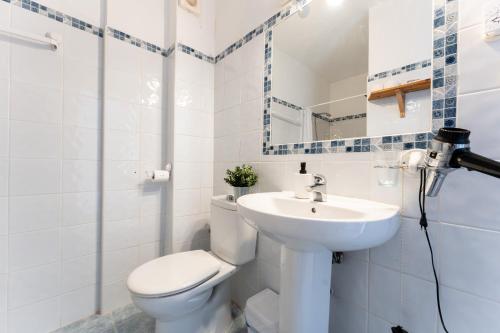 a white bathroom with a toilet and a sink at Ventana al mar in Fuengirola