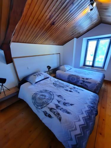 two beds in a bedroom with a wooden ceiling at Chambre et Table d’Hôtes du Terroir in Borne