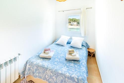 a bedroom with a bed with two pillows and a window at Sa Barca - Can Ferrando in Cala Santanyi