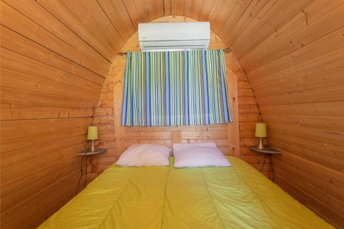 a small bed in a wooden room with a window at Pod Anis in Saint-André