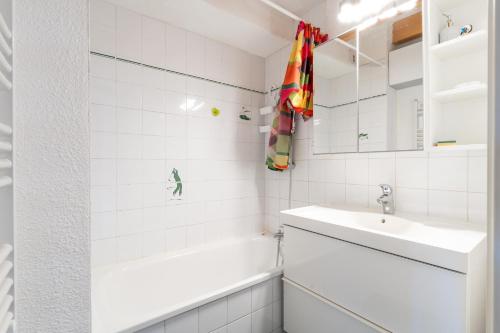 a white bathroom with a sink and a bath tub at La Cabine du Marin - 73 in Pornic