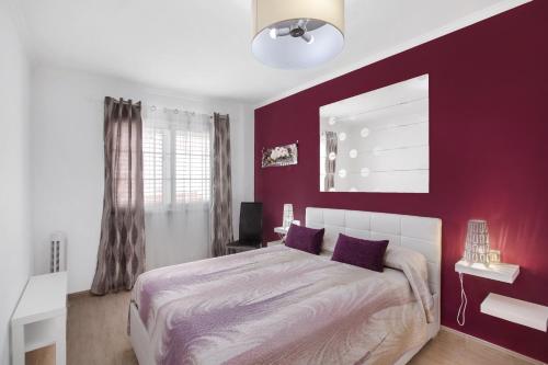 a bedroom with red walls and a bed with purple pillows at Apartamento Porís in Arico