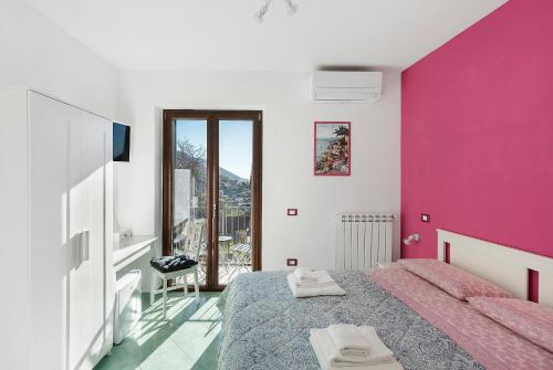 a bedroom with a bed and a pink wall at Coast 2 Coast in Agerola