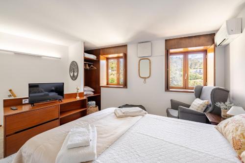 a bedroom with a bed and a tv and a chair at Casa à Beira da Água Gerês in Geres