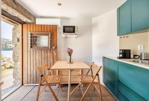a kitchen with a wooden table and chairs in a kitchen at Casa à Beira da Água Gerês in Geres