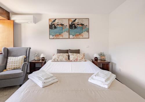 a white bedroom with a bed and a chair at Casa à Beira da Água Gerês in Geres