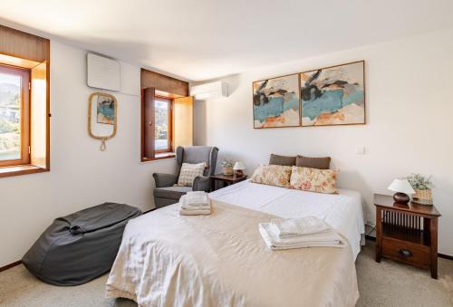 a bedroom with a large bed and a chair at Casa à Beira da Água Gerês in Geres
