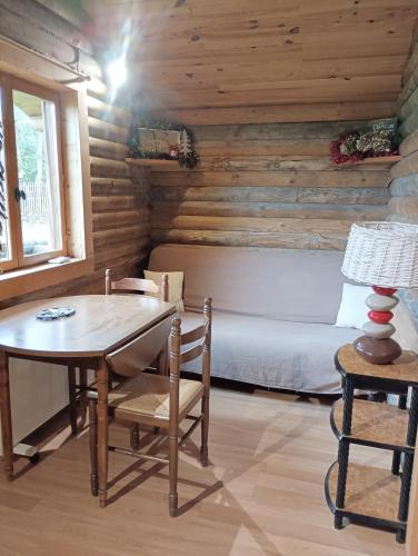 a room with a table and a bed in a log cabin at Chalet Idéal Randonnée in La Chapelle-Yvon
