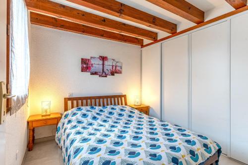 a bedroom with a bed with a blue and white comforter at La maison des Prairies - Biscarosse in Biscarrosse