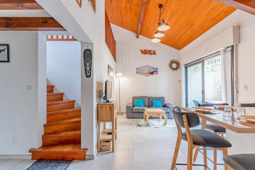 a living room with a staircase and a table and chairs at La maison des Prairies - Biscarosse in Biscarrosse