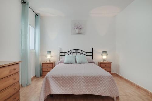 a bedroom with a bed with two night stands and two lamps at Piso Ana Paula 1 in Conil de la Frontera