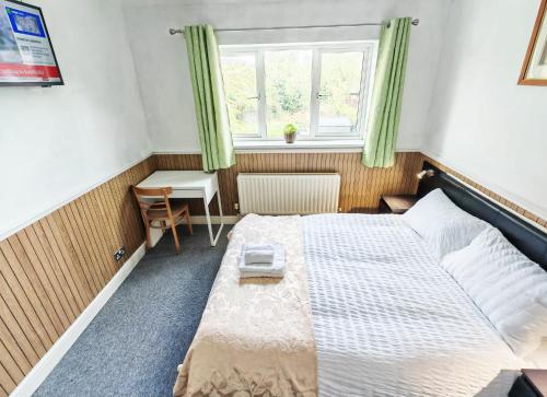 a bedroom with a bed and a desk and a window at Azalea Studio - Self Contained One-Bed Studio Flat in Oxford