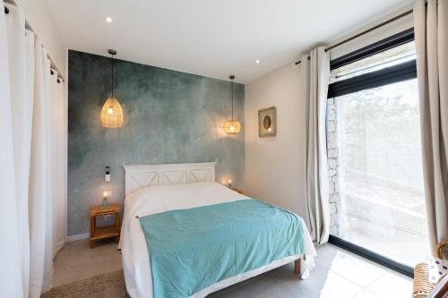 a bedroom with a bed and a large window at A Chiusella in Belgodère