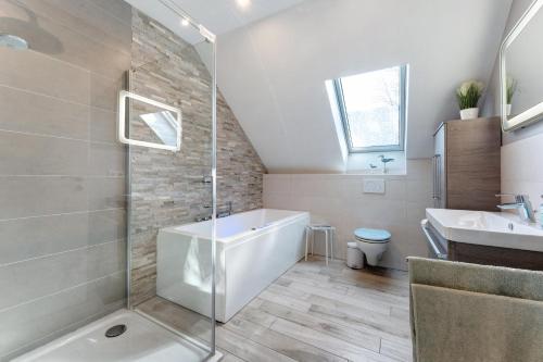 a bathroom with a tub and a sink at Feriendoppelhaus Frühling in Stakendorf
