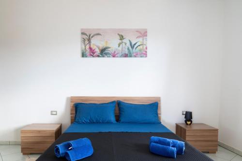 a bedroom with a bed with blue pillows and a painting at Casa Cuccureddu in Jerzu