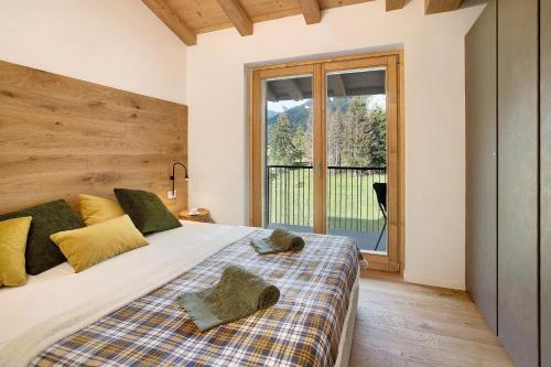 a bedroom with a bed and a large window at Violet a due passi da Bormio in Valdidentro