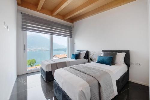 two beds in a room with a large window at Luxury Lakefront Penthouse in Lezzeno
