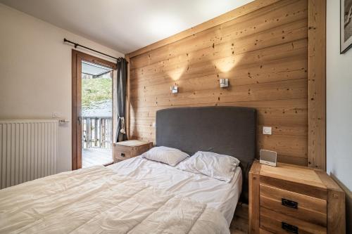 a bedroom with a bed and a wooden wall at Les loges blanches204 centre chatel in Châtel