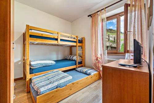a bedroom with bunk beds and a desk with a computer at Appartamento Collini Le Betulle in Spiazzo
