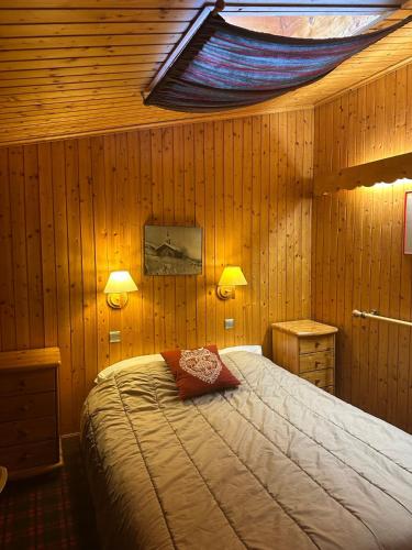 a bedroom with a bed in a wooden wall at Duplex Méribel Mottaret 8 personnes in Les Allues