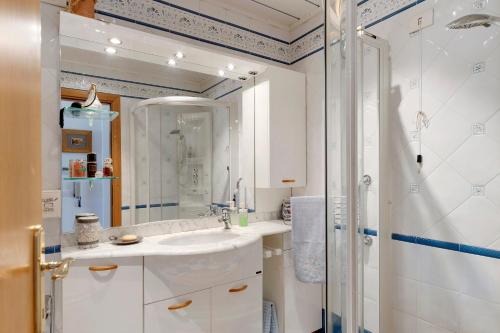 a white bathroom with a shower and a sink at Appartamento Moser P in Levico Terme
