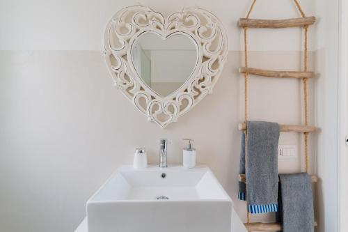 a bathroom with a white sink and a heart mirror at Dimora Balu' in Parabita
