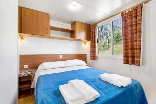 a bedroom with a blue bed with two towels on it at Camping Royal in Pettenasco