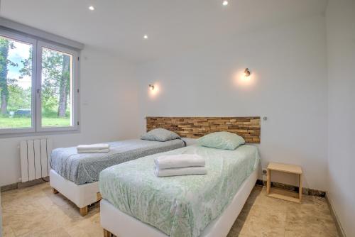 two beds in a room with two windows at Gite Deodatus avec piscine in Cladech