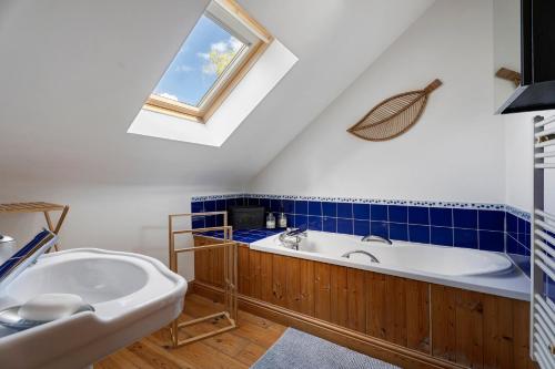 a bathroom with a tub and a sink and a window at Le Fenil gîte avec piscine partagée in Saint-Thual