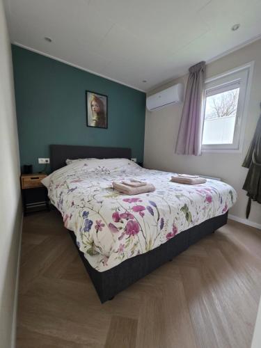 a bedroom with a bed with a floral bedspread at Sallands Boschalet in Haarle