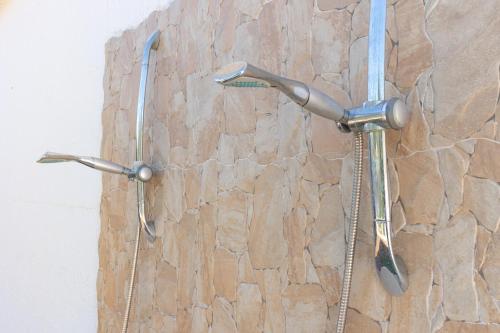 a shower in a bathroom with a stone wall at Dimora Home Sweet Home with Private Pool in Putignano