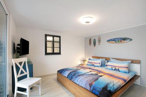 a bedroom with a bed and a white chair at Häuser am See in Königs Wusterhausen