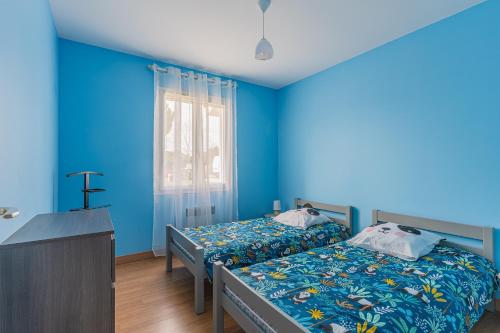a bedroom with two beds and a blue wall at Le Pin Franc in Valeyrac