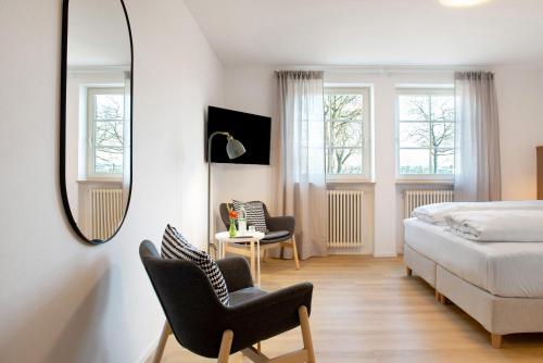 a bedroom with a bed and two chairs and a mirror at Gästehaus Schwert in Salem