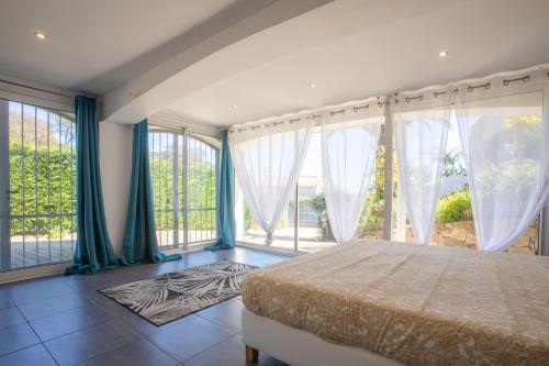 a bedroom with a bed and large windows at Villa Palmier avec piscine in Roquebrune-sur-Argens