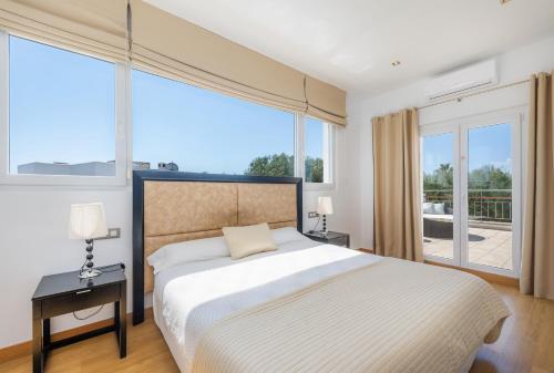 a bedroom with a large bed and large windows at Villa Beatriz in Cala d´Or