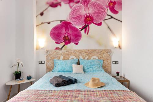 a bedroom with a bed with purple flowers on the wall at Suite Jinetes in Málaga
