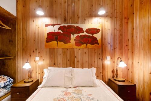 a bedroom with a bed with two lamps and a painting on the wall at Cantinho do Sossego in Várzea