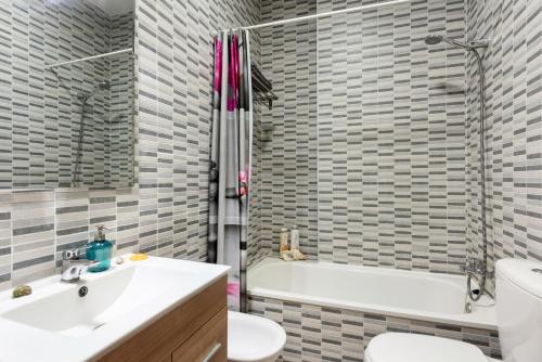 a bathroom with a sink and a toilet and a tub at Suite Jinetes in Málaga