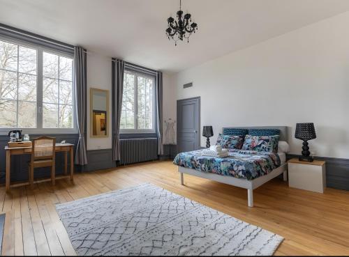 a bedroom with a bed and a desk and windows at Château De Saint Mayeul in Joze