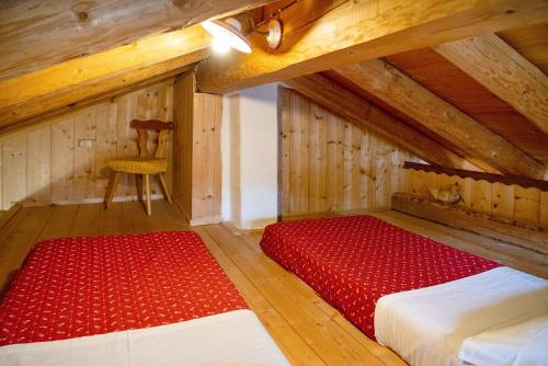 an attic room with two beds and a chair at Appartamenti Marmolada Falcade in Falcade