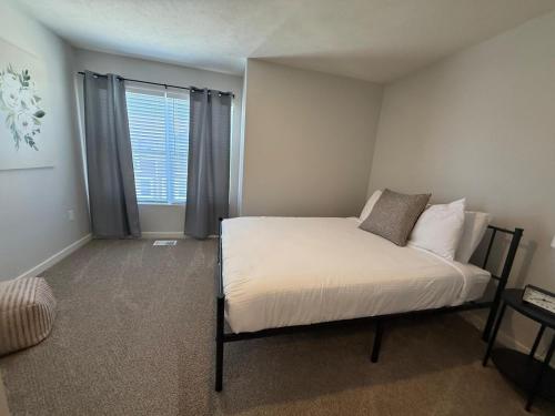 a bedroom with a bed with white sheets and a window at The Meadowlark at Coventry Rows in Omaha