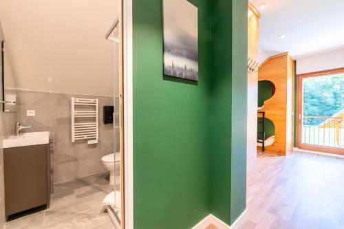 a bathroom with a green wall and a toilet at Hostel du Val de Tamié in Faverges