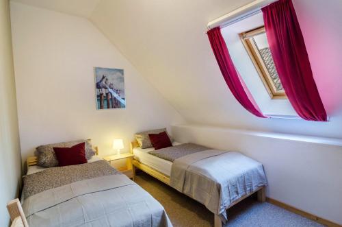 two beds in a small room with a window at Gulfhof Oldersum Dachgeschoss in Moormerland