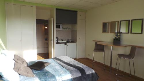 a bedroom with a bed and a table and a kitchen at Studios étape du Lac in Bourbon-Lancy