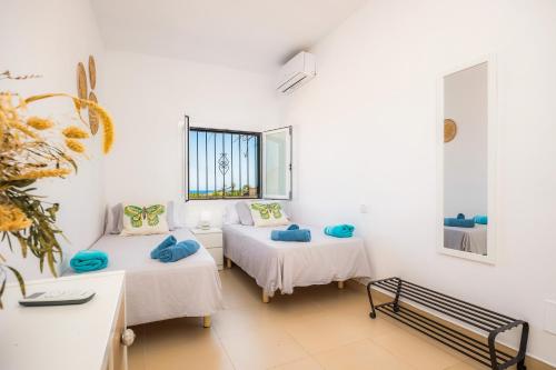 a white room with two beds and a window at Finca Blanca in Calas de Mallorca