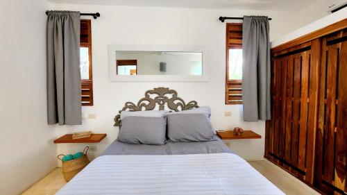 a bedroom with a bed with a mirror and windows at Casa Lowen Villa with Private Pool in Las Terrenas
