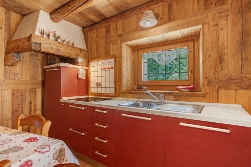 a kitchen with red cabinets and a sink at Maison Peroulaz Charvensod in Charvensod