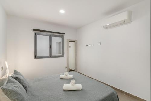 a white bedroom with two towels on a bed at Edificio Bentejui 2 in Las Palmas de Gran Canaria